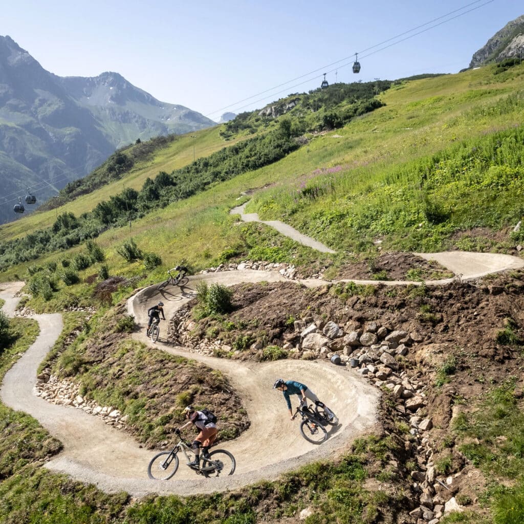 Vier Radfahrer fahren auf einem sonnigen Bergweg und genießen ihren Sommerurlaub in Ischgl.